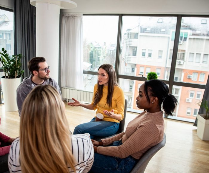 Diverse group of people sitting in circle in group therapy session.